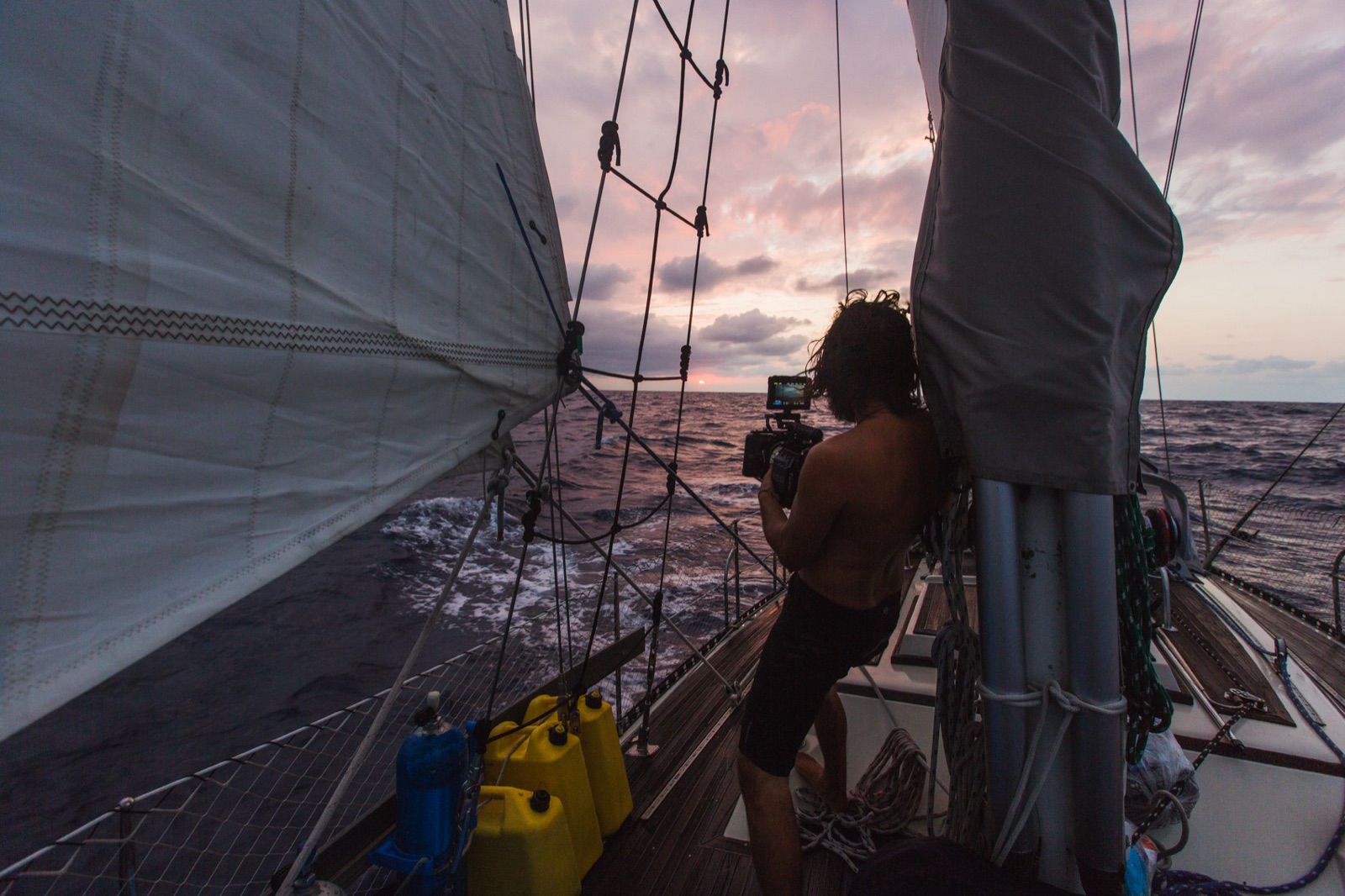 Andrew Tomayko filming from the bow of his sailboat at sunset